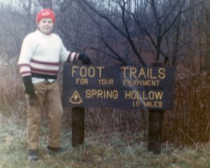 Young man standing next to park sign